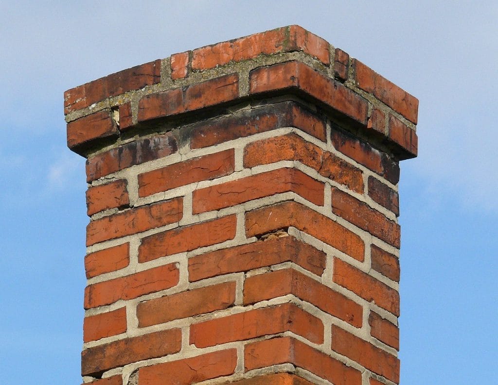 A historic red brick chimney in need of some repair